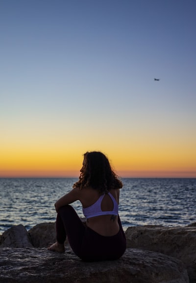 Prime-time woman sat on a rock face to the sea
